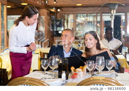 Positive young couple making order at restaurant Positive young couple making order at restaurant 98136600