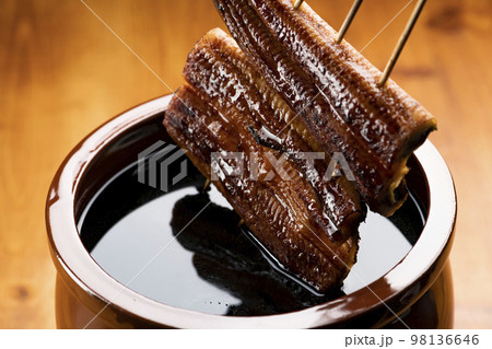 鰻の蒲焼きを秘伝のタレに漬ける 鰻の蒲焼きを秘伝のタレに漬ける 98136646