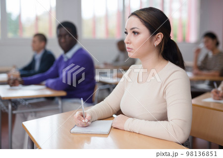 Young woman studying with colleagues at classroom Young woman studying with colleagues at classroom 98136851