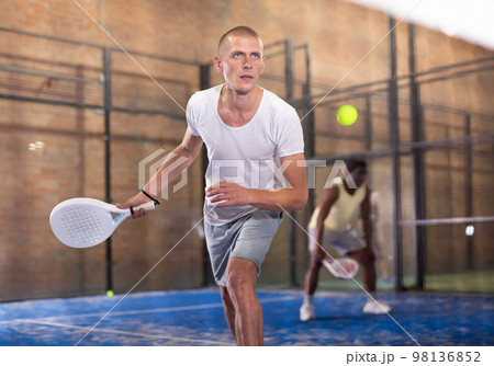 Concentrated paddle tennis player preparing to hit forehand Concentrated paddle tennis player preparing to hit forehand 98136852