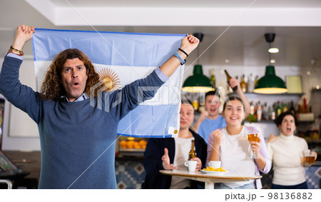 Joyful fans of the Argentina team celebrating the victory in night bar 98136882