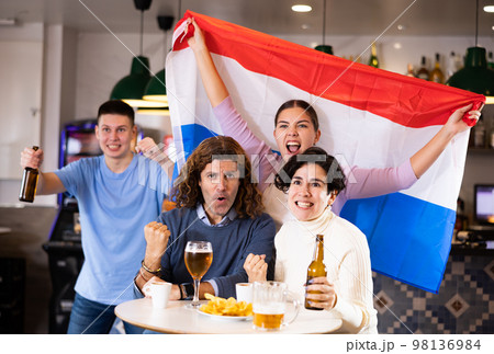 Fans with flag of Netherlands celebrate victory of their favorite team in beer bar 98136984