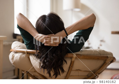 Rear view of relaxed black haired woman resting in armchair 98140162