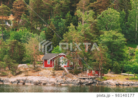 Sweden. Beautiful Red ASwedish Wooden Log Cabins Houses On Rocky Island Coast In Summer. Lake Or River Landscape Sweden. Beautiful Red ASwedish Wooden Log Cabins Houses On Rocky Island Coast In Summer. Lake Or River Landscape 98140177