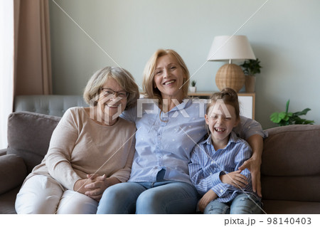 Girl and senior women of female generations resting on couch 98140403