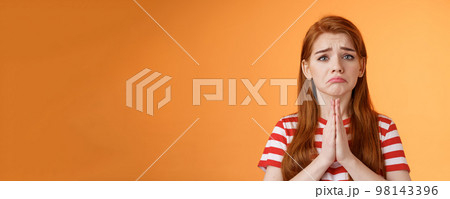 Pity uneasy redhead girl pull sad face, quivering lip upset, begging mercy, apologizing, plead help, press palms pray gesture, frowning hopeless, asking and begging favour, stand orange background Pity uneasy redhead girl pull sad face, quivering lip upset, begging mercy, apologizing, plead help, press palms pray gesture, frowning hopeless, asking and begging favour, stand orange background 98143396