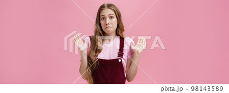 I am not involved. Portrait of unaware and clueless innocent cute woman raising palms in surrender pulling lips down as if being confused and uncertain what happening having no idea over pink wall I am not involved. Portrait of unaware and clueless innocent cute woman raising palms in surrender pulling lips down as if being confused and uncertain what happening having no idea over pink wall 98143589