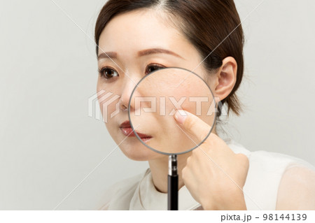 女性の肌をルーペで拡大している。 女性の肌をルーペで拡大している。 98144139