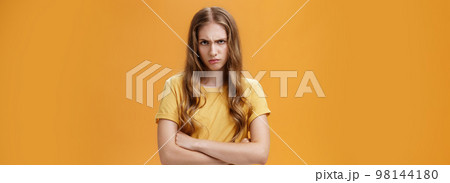 Girl mad like devil. Portrait of angry bothered and offended hateful young woman looking from under forehead frowning and sulking crossing arms against chest in defensive pose, scorning offender 98144180