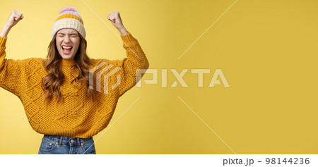 Relieved attractive fashionable university female student yelling proudly raise clenched fists victory cheer gesture celebrating win successful achievement accomplishment goal, yellow background Relieved attractive fashionable university female student yelling proudly raise clenched fists victory cheer gesture celebrating win successful achievement accomplishment goal, yellow background 98144236