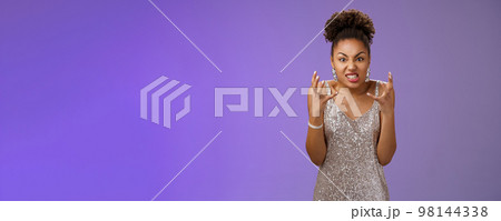 Annoyed pissed arrogant freak-out african american woman in silver dress squeeze fists angry frowning grimacing anger furiously look camera bothered yell rage react outrageous disrespect 98144338