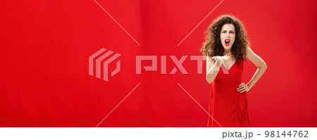How dare you betray me. Pissed outraged bossy and displeased european adult woman with curly hairstyle in elegant dress bending towards camera with raised palm, complaining blaming and judging How dare you betray me. Pissed outraged bossy and displeased european adult woman with curly hairstyle in elegant dress bending towards camera with raised palm, complaining blaming and judging 98144762