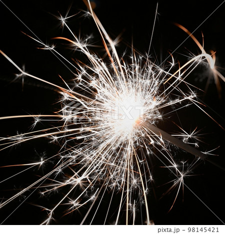 Christmas background. A sparkler on a Christmas tree in the evening outside with snow. Concept for winter season, holidays and new year 2023. Christmas background. A sparkler on a Christmas tree in the evening outside with snow. Concept for winter season, holidays and new year 2023. 98145421