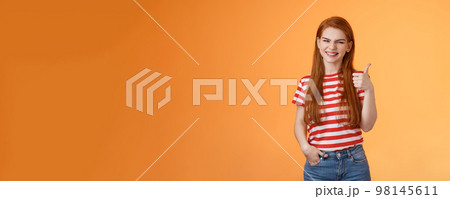 Cheerful friendly woman red natural hair clean skin, show thumb up, smiling approval, support perfect choice, like excellent performance, express positive opinion, acceptance, orange background Cheerful friendly woman red natural hair clean skin, show thumb up, smiling approval, support perfect choice, like excellent performance, express positive opinion, acceptance, orange background 98145611