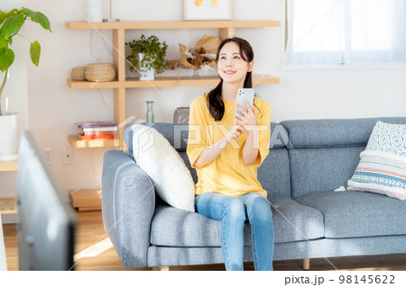 部屋でスマホを操作する若い女性 部屋でスマホを操作する若い女性 98145622