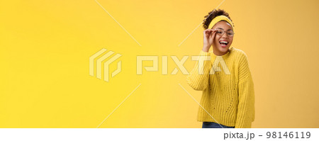 Charismatic stylish confident beautiful african-american joyful teenage girl touching glasses nose laughing broadly look down right corner grinning have fun joking enjoying, yellow background 98146119