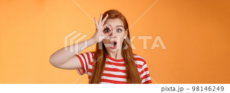 Surprised excited shocked young redhead girl gasping impressed look through okay circle, stare camera astonished awesome sale, open mouth say wow thrill and amazement, orange background Surprised excited shocked young redhead girl gasping impressed look through okay circle, stare camera astonished awesome sale, open mouth say wow thrill and amazement, orange background 98146249