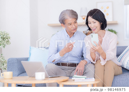 スマホを見ながら談笑するミドル夫婦 98146975
