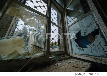 Broken window of desolate building 98148650