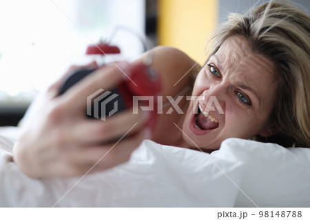 Woman looks at alarm clock and yells to bed Woman looks at alarm clock and yells to bed 98148788