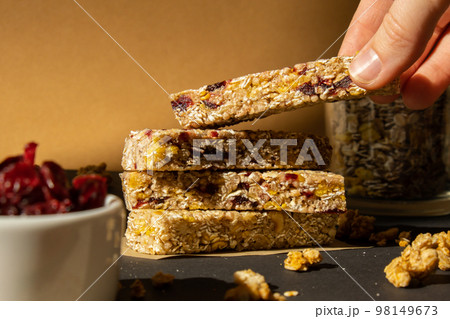 Woman takes Homemade Granola energy bar. Variety of protein granola breakfast bars, with nuts, raisins dried cherries and chocolate. Healthy nutrition eating Gluten free cereal dieting snack super Woman takes Homemade Granola energy bar. Variety of protein granola breakfast bars, with nuts, raisins dried cherries and chocolate. Healthy nutrition eating Gluten free cereal dieting snack super 98149673