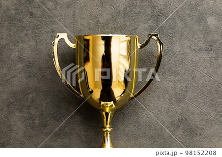 Simply flat lay design winner or champion gold trophy cup on concrete stone grey background. Victory first place of competition. Winning or success concept. Top view copy space Simply flat lay design winner or champion gold trophy cup on concrete stone grey background. Victory first place of competition. Winning or success concept. Top view copy space 98152208