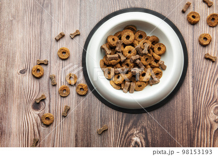 A bowl of dog food on a wooden floor. 98153193