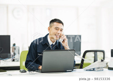 オフィスで電話対応する作業服の男性 98153336