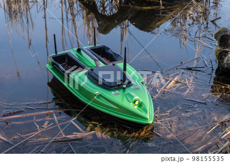 Bait Boat on water. Wireless remote control green fishing feeder, fish finder boat. Bait Boat on water. Wireless remote control green fishing feeder, fish finder boat. 98155535
