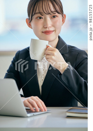 デスクでコーヒーを飲みながら休憩をする若い女性 デスクでコーヒーを飲みながら休憩をする若い女性 98155725