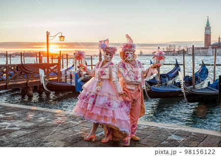 Colorful carnival masks against gondolas at a traditional festival in Venice, Italy 98156122