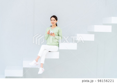 階段でスマホを見る若い女性 98156221