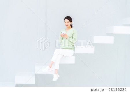 階段でスマホを見る若い女性 98156222