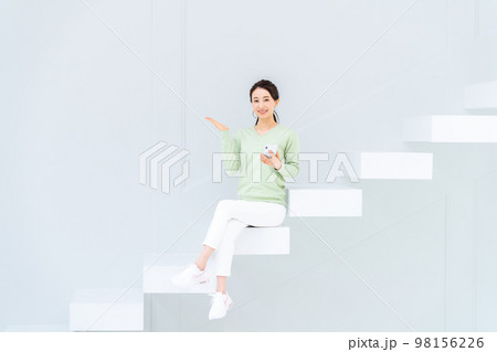 階段でスマホを見る若い女性 98156226