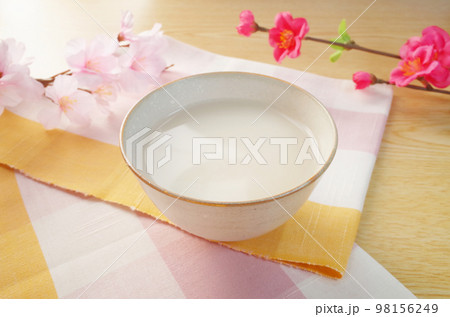 陶器に注がれた甘酒のシーン 桜と梅の花とピンクのチェックの伊勢木綿 陶器に注がれた甘酒のシーン 桜と梅の花とピンクのチェックの伊勢木綿 98156249