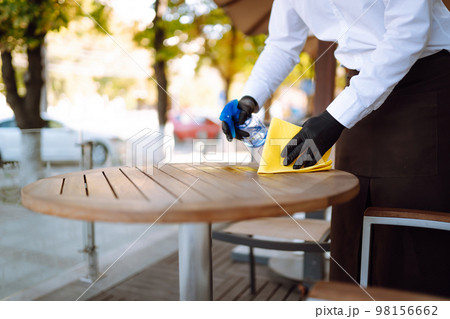 Disinfecting to prevent COVID-19. Waiter cleaning the table with Disinfectant Spray in a restaurant. 98156662