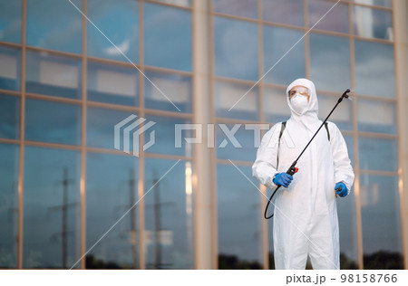 Disinfecting to prevent COVID-19, Man in protective hazmat suit with spray chemicals. Cleaning 98158766