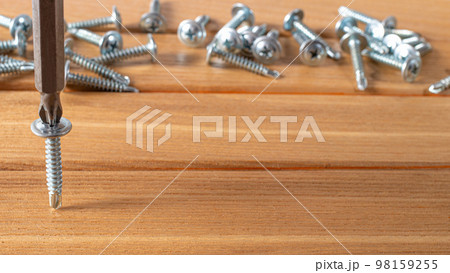 The screwdriver twists the self-cut into wooden boards. Construction tools, home repairs. The screwdriver twists the self-cut into wooden boards. Construction tools, home repairs. 98159255