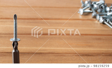 A screwdriver and self-cutters on a brown wooden background. Building tools to repair the house. A screwdriver and self-cutters on a brown wooden background. Building tools to repair the house. 98159259