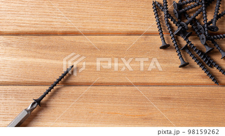 A screwdriver and self-cutters on a brown wooden background. Building tools to repair the house. 98159262