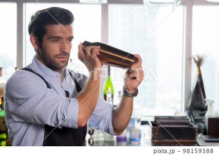 Young caucasian man is bartender holding and shaker for mixing beverage preparation serving. Young caucasian man is bartender holding and shaker for mixing beverage preparation serving. 98159388