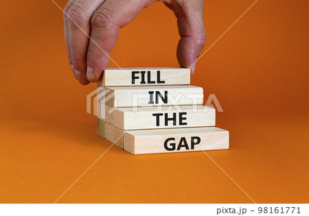 Fill in the gap symbol. Concept words Fill in the gap on wooden blocks on a beautiful orange table orange background. Businessman hand. Business, motivational and fill in the gap concept. 98161771