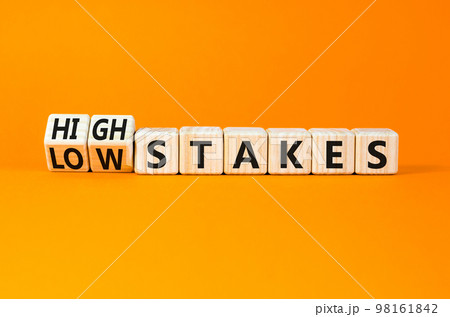High or low stakes symbol. Concept words High stakes and Low stakes on wooden cubes. Beautiful orange table orange background. Business high or low stakes concept. Copy space. 98161842