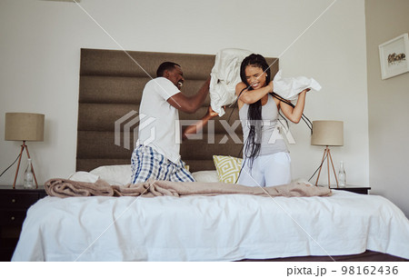 Love, pillow fight and playful with a black couple having fun in the bedroom of their home tofether in the morning. Dating, funny and joking with a man and woman playing or bonding on the bed 98162436