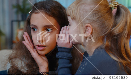 Teenage child whisper news rumors in ear to little sister kid girl share secrets gossip having fun Teenage child whisper news rumors in ear to little sister kid girl share secrets gossip having fun 98162689