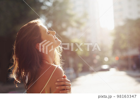 Enjoying the sun on her skin. an attractive young woman in an urban setting. Enjoying the sun on her skin. an attractive young woman in an urban setting. 98163347