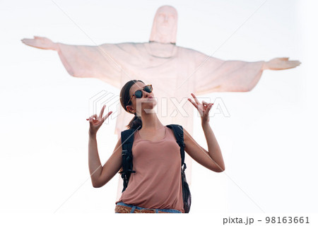 Feeling the Rio vibe. a woman posing for a picture in front of a statue of Christ in Brazil. 98163661