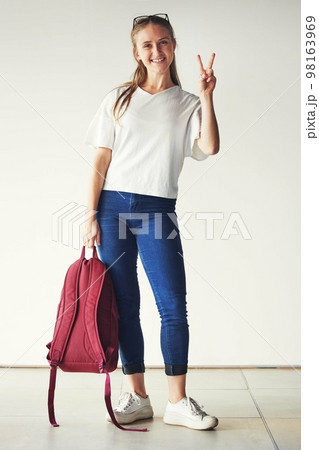 Woman, student and backpack with peace sign in portrait before college, school or university in house. Girl, learning or happy in home with bag ready for education, travel and hand gesture with smile Woman, student and backpack with peace sign in portrait before college, school or university in house. Girl, learning or happy in home with bag ready for education, travel and hand gesture with smile 98163969