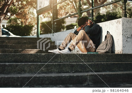 Sad, depression and black man with anxiety at college, stress and headache from education on the stairs at campus. Depressed, frustrated and student with a mental health problem crying at university 98164046