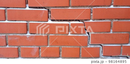 The red brick wall cracked. Crack on the red wall. The red brick wall cracked. Crack on the red wall. 98164895